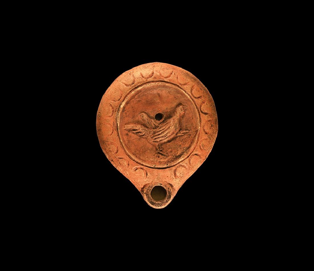 Roman Oil Lamp with Cockerel: 1st-2nd century AD. A terracotta squat oil lamp with basal ring, broad piriform body with low nozzle, band of crescents to the shoulder, high-relief cockerel to the discus. See Bémont, C. Lampes en T