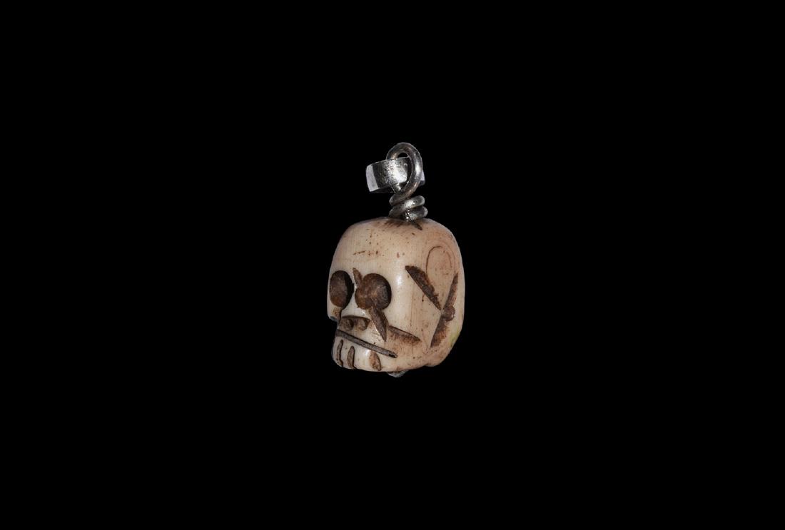 Jacobean Silver and Bone Skull Pendant: 17th century AD. A bone pendant of a skull, engraved details to the face; twisted silver wire through, with suspension ring. 3.23 grams, 22mm (3/4"). From an old North Country collection; formed betwe