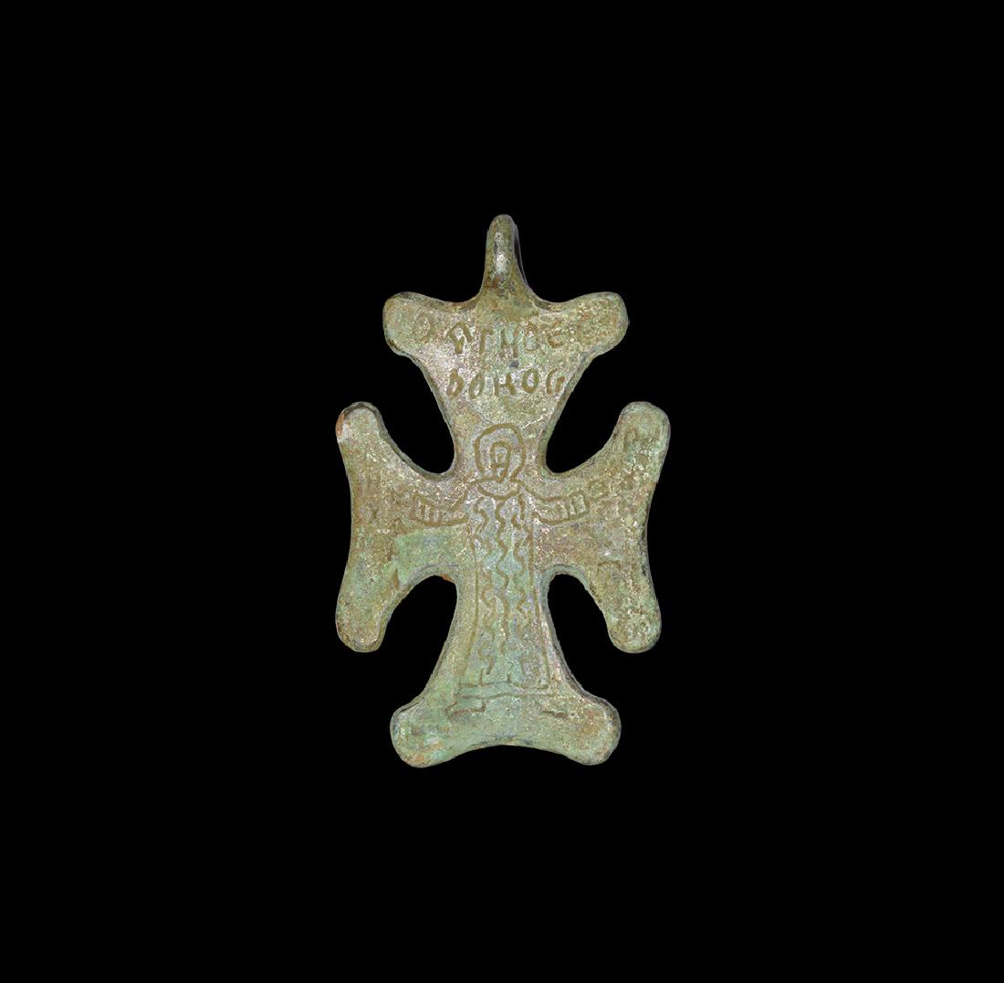 Byzantine Cross Pendant: 10th-11th century AD. A flat-section bronze cruciform pendant with expanding arms and lobe to each angle, low-relief image of a nimbate figure with arms spread, text above and to each side. 37 grams, 