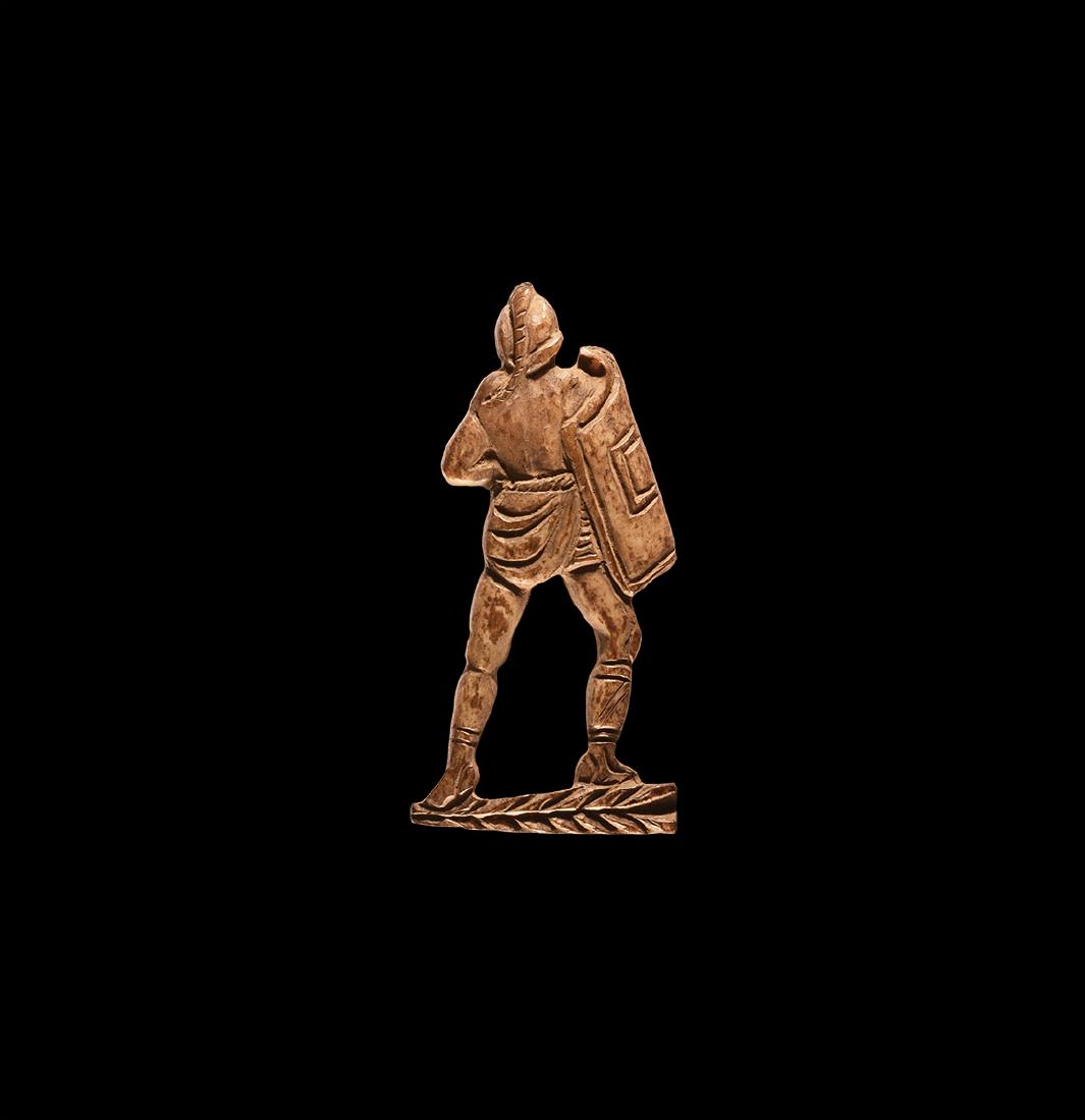 Roman Bone Gladiator AppliquÃ©: 1st-2nd century AD. A bone appliquÃ© of a secutor gladiator shown from the rear, with square curved shield, crested helmet, loincloth and boots, standing on a herringbone base. 13 grams, 67mm (2 3/4
