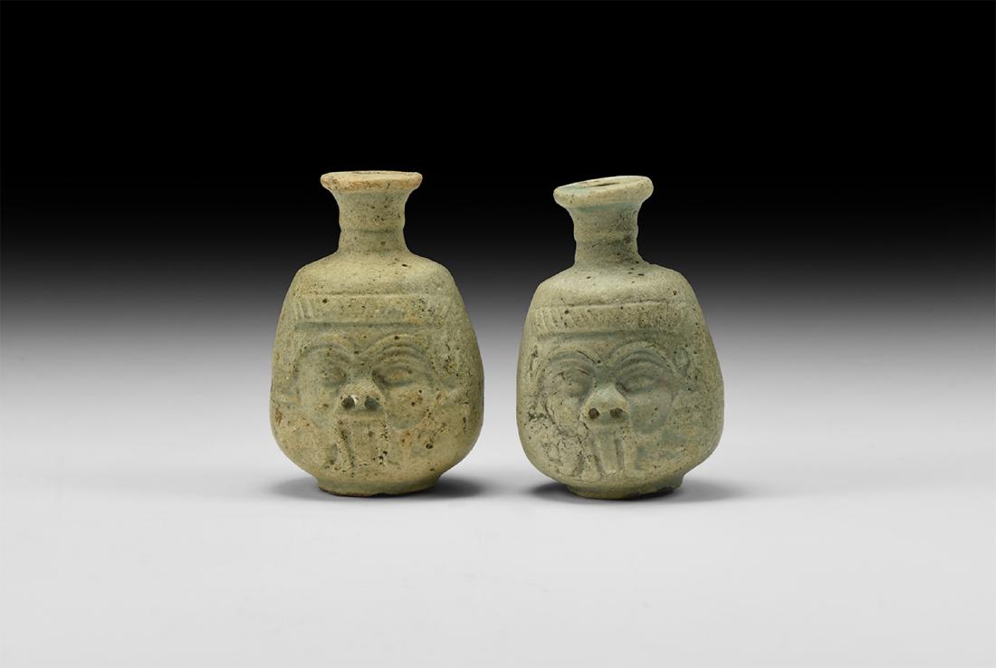 Egyptian Bes Flask Pair: Ptolemaic Period, 332-30 BC. A pair of glazed composition flasks; narrow spout with flat rim; globular body with face of Bes to the front, arching eyebrows, snub nose, tongue sticking out and beard to