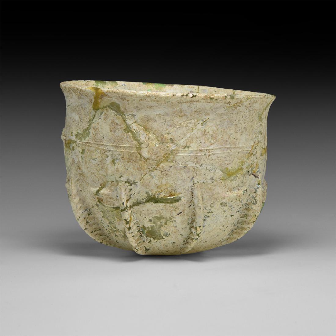 Sassanian Ribbed Glass Cup: 3rd-7th century AD. A glass bell-shaped cup with chamfered rim, ten ribbed flanges to the underside with interstitial pinched ledges below the equator, some iridescence remaining. 155 grams, 11.4cm di