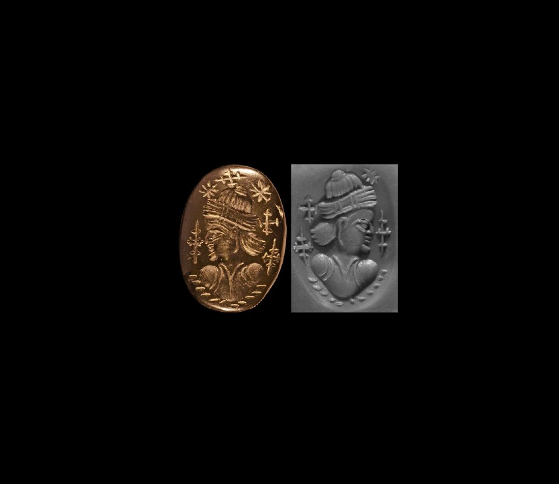 Sassanian Gemstone with Male Bust: 3rd-7th century AD. A carved haematite(?) cabochon with intaglio to the flat face, profile male bust with segmented headdress, surrounded by crosses potent and starbursts. 3.14 grams, 19.66mm (3/4"). 