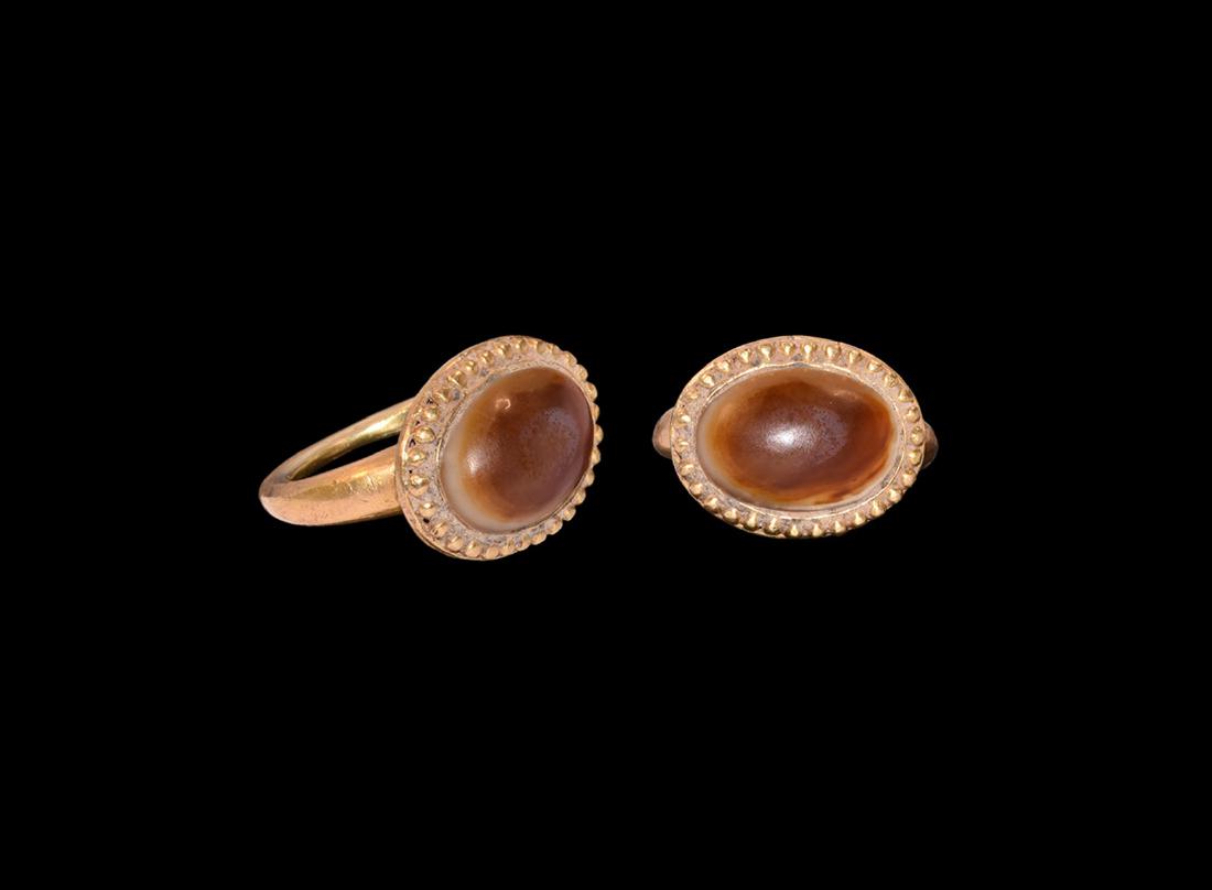 Post Medieval Gold Ring with Agate Gemstone: 19th-20th century AD. A gold ring comprising a round-section hoop, ellipsoid bezel with beaded rim, inset banded agate cabochon. 11 grams, 32mm overall, 19.81mm internal diameter (approximate size Bri