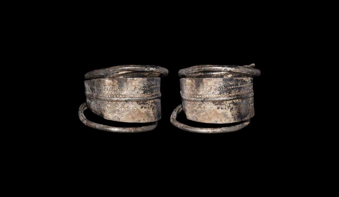 Viking Coiled Tremello Ring: 10th-12th century AD. A sheet silver finger ring with median hoop extending to two round-section bars coiled to the edges of the flat-section flanges; geometric tremello-style motifs to the flanges; B