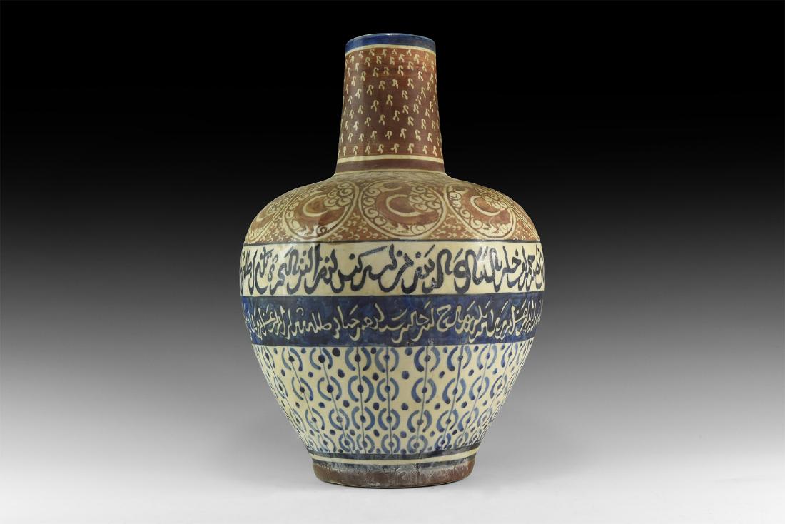 Islamic Calligraphic Vase: An undated archaistic glazed ceramic jar with deep shoulder and tall cylindrical neck; bands of calligraphic text to the shoulder, body and base of the neck with roundels to the shoulder each framing 