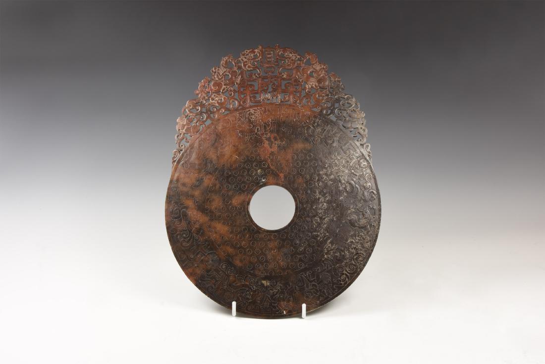Chinese Carved and Engraved Roundel: 20th century AD. A carved stone(?) roundel with openwork fringe of horsemen, lions, characters and scrolls, frieze of dragons and other beasts in low-relief to the disc. 702 grams, 32cm (12 1/2"). Lon