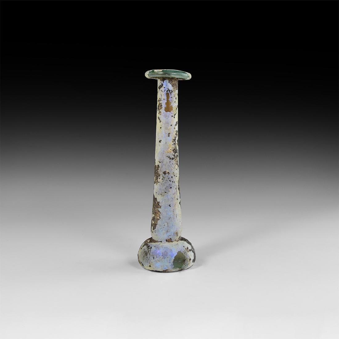 Roman Tall Glass Vessel: 1st-3rd century AD. A glass unguentarium perfume bottle with squat domed body and recessed underside, tapering neck with splayed and folded rim; some iridescence to surface. Cf. Whitehouse, D. Roman G