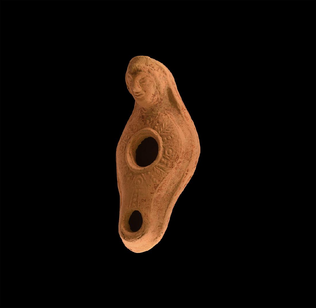Byzantine Oil Lamp with Figural Handle: 6th-10th century AD. A slipper-shaped oil lamp with pellet and line decoration on the upper surface, the handle formed as a female head with curled hair, wearing a headdress with veil, pellet-and-annu