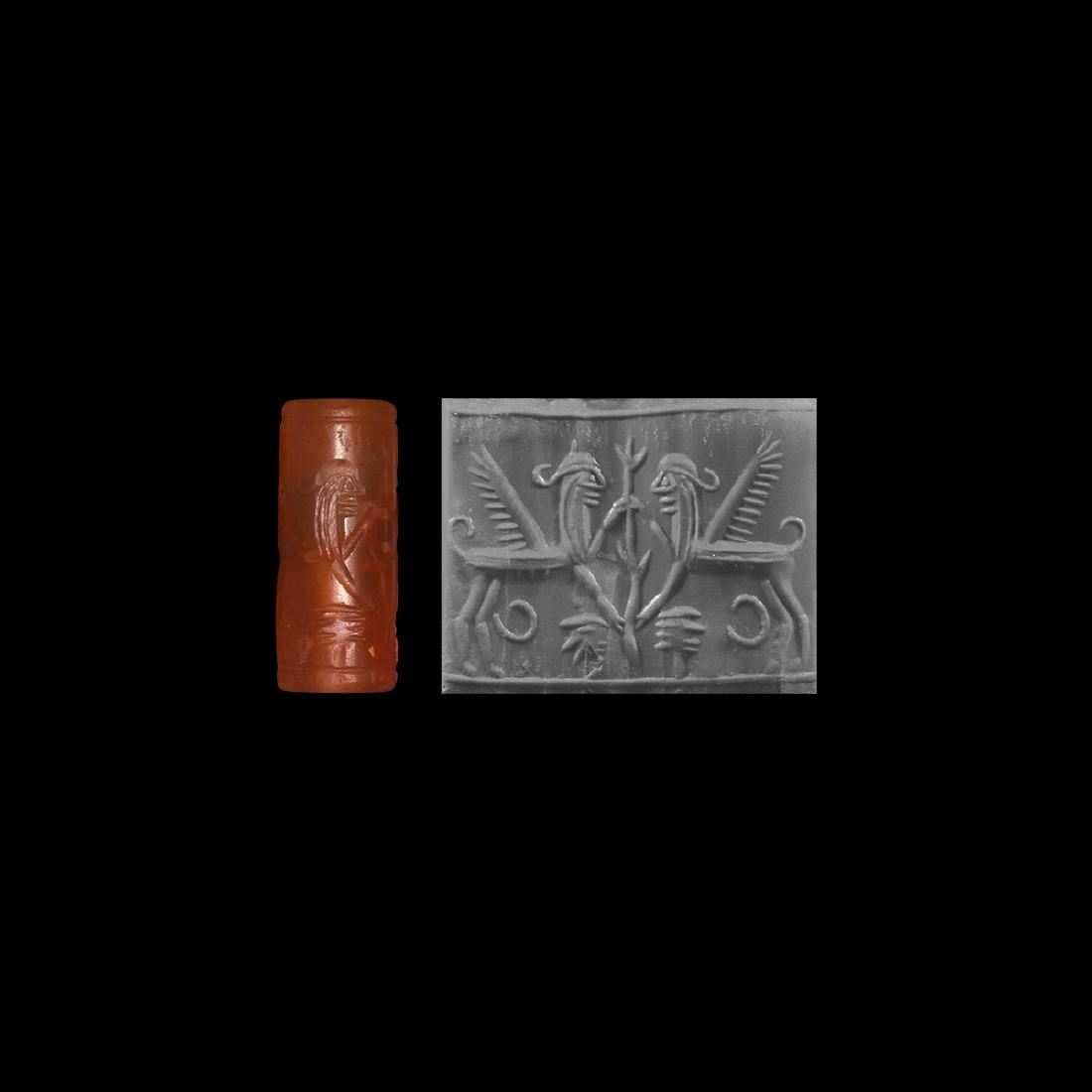 Syro-Cypriot Cylinder Seal with Tree / Sphinxes: 16th-13th century BC. A carved carnelian cylinder seal with stylised tree in the form of a plant stem which is flanked by two sphinxes facing each other, and embracing the tree above and below with ar