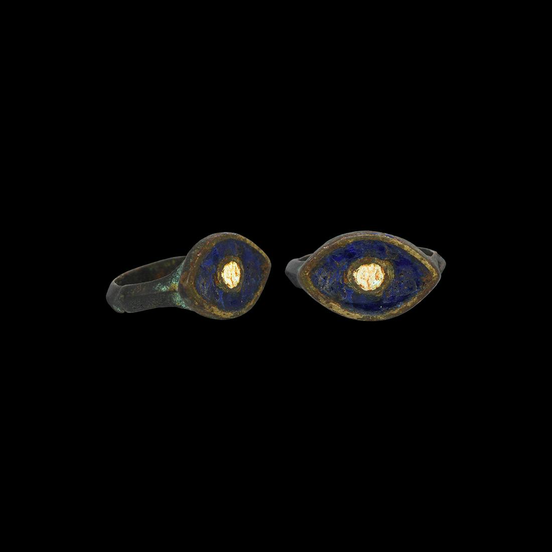 Egyptian Ring with Eye: Ptolemaic Period, 332-30 BC. A bronze scaphoid bezel with blue enamel fill, central white enamel 'eye', cusped D-section shank with lateral stepped panels. Cf. Chadour, A.B. Rings. The Alice and Louis