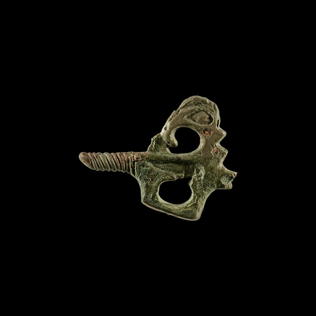 Scythian Dolphin Pendant: 2nd-3rd century BC. A bifacial bronze pendant depicting a leaping dolphin to one side and a 'trumpet' style motif to the other; spiralled shank to the lower tail; upper suspension loop absent. See R. 