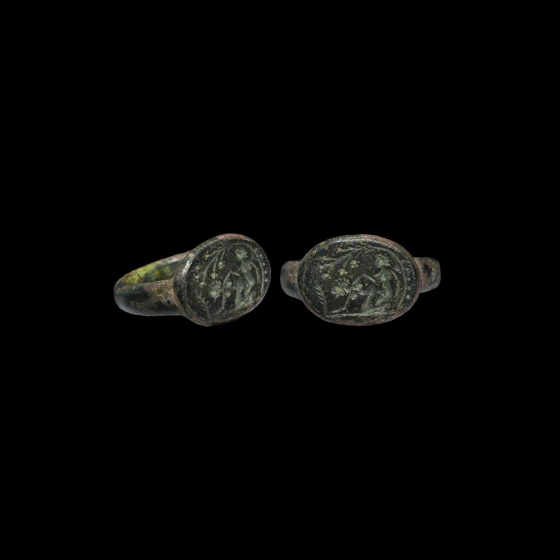 Roman Ring with Erotic Scene: 2nd century AD. A large bronze D-section hoop with raised oval bezel, intaglio image of a couple engaged in coitus under a fruit tree, palm leaf to the front. 10.34 grams, 27.3mm overall, 20mm interna