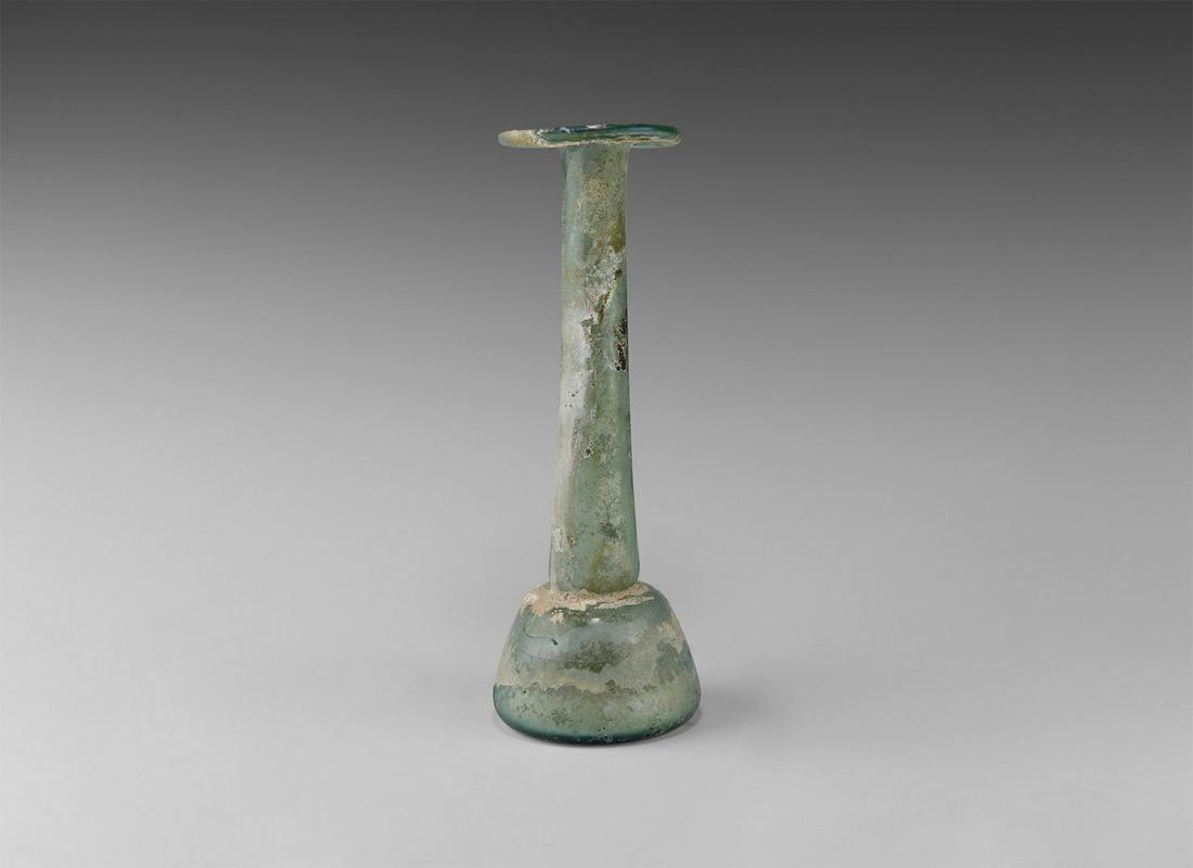 Roman Tall Glass Vessel: 1st century AD. A glass unguentarium perfume bottle with squat domed body and slightly recessed underside, long slender neck with splayed and folded rim; some iridescence to surface. Cf. Whitehouse, D