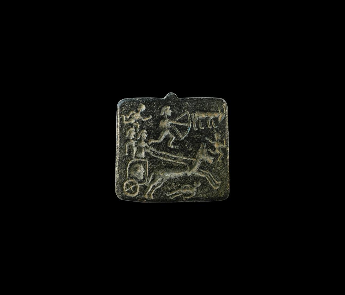 Western Asiatic Pendant Seal with Hunting Scene: 3rd millennium BC. A carved square serpentine seal with intaglio hunting scene including a bowman chasing a deer and a two-wheeled chariot drawn by a horse. 26 grams, 36mm (1 1/2"). Property of a Lond