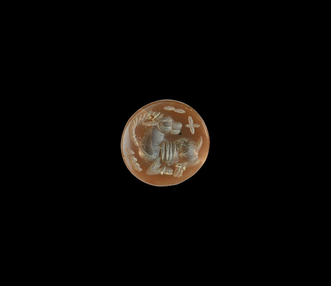 Western Asiatic Sassanian Gemstone with Ibex: 3rd-7th century AD. A discoid carnelian intaglio with recumbent ibex, objects in the field. 1.48 grams, 16mm (1/2"). Property of a North London gentleman; acquired on the UK art market before 2000. [N