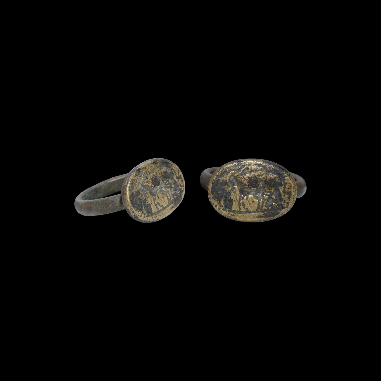 Signet Ring with Animal and Figure: 1st millennium BC. A bronze finger ring with ellipsoid bezel, intaglio scene with a quadruped in profile and seated figure. 6.79 grams, 23mm overall, 18.21mm internal diameter (approximate size Britis