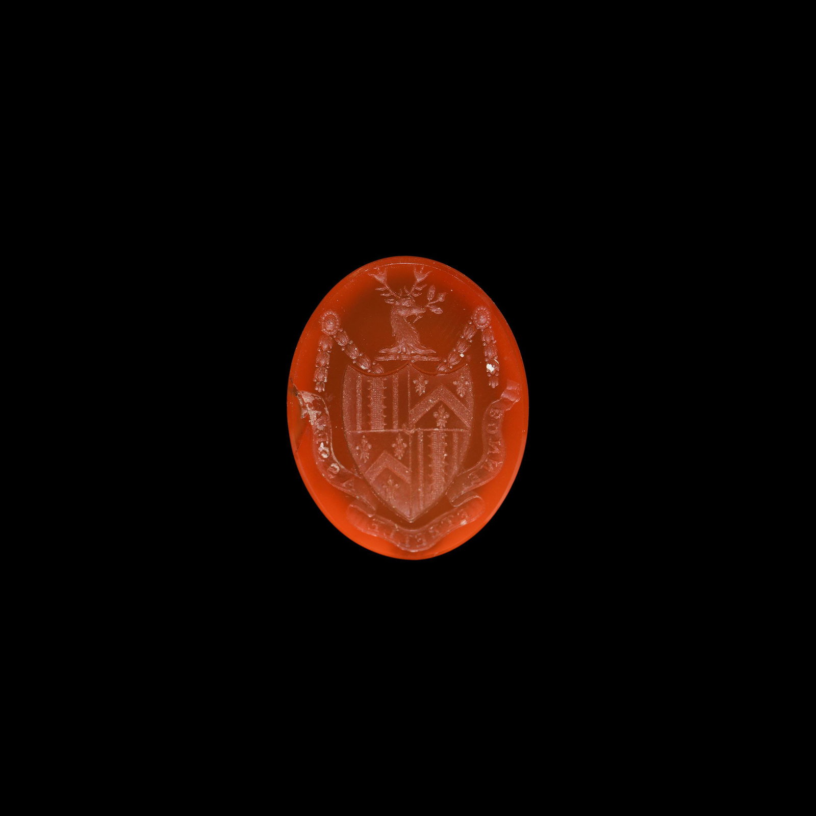 Georgian Picard Family Armorial Seal Stone: 18th century AD. A carnelian cloison with intaglio with intaglio armorial bearing, heater shield beneath a stag's head crest with quartered arms of a chevron between crosses and paly field, motto on a