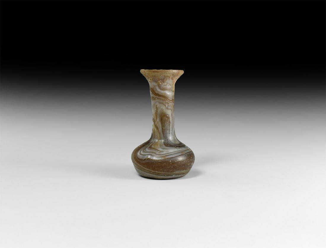 Roman Marbled Amber Glass Vase: 1st century AD. A marbled amber glass toilet bottle with squat body and dimpled base, long neck and flared mouth with rolled rim. Cf. Whitehouse, D. Roman Glass in the Corning Museum of Glass, vol.1,