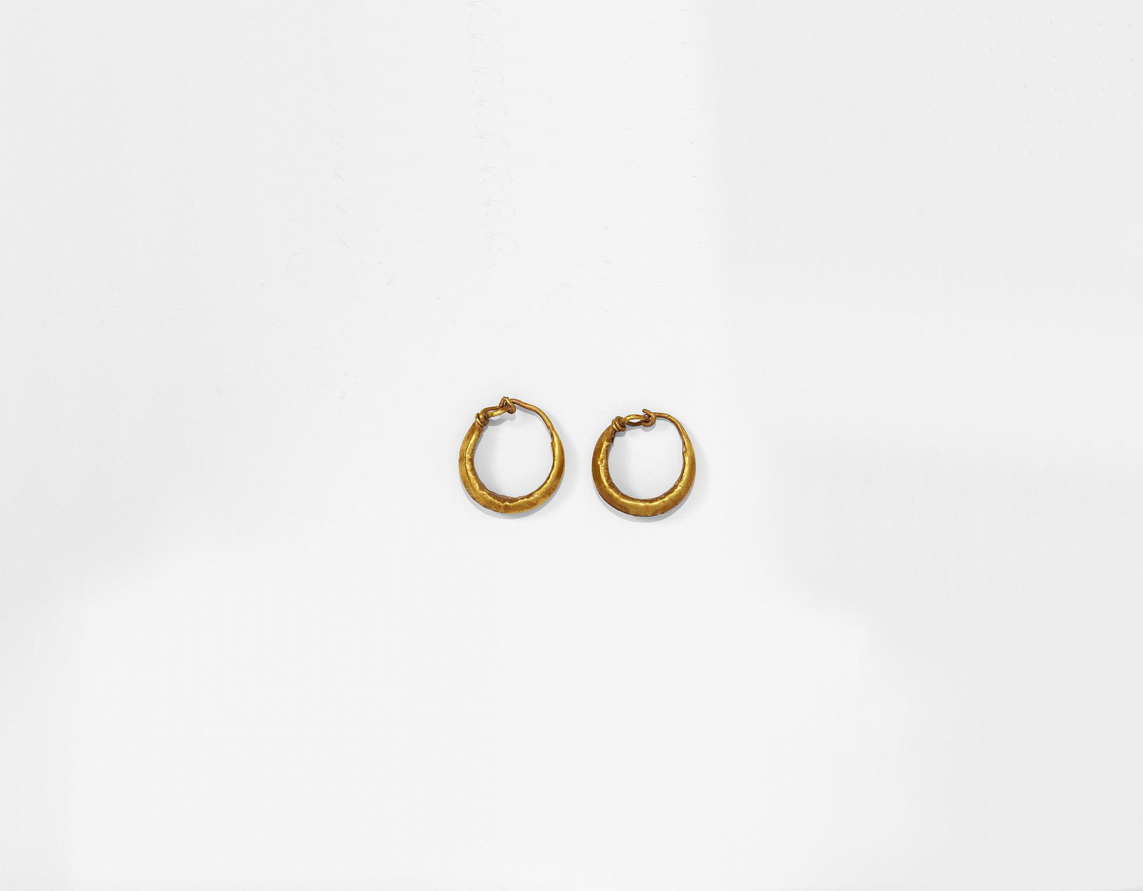 Roman Gold Hoop Earring Pair: 1st-2nd century AD. A matched pair of hollow-formed gold crescent earrings with looped finials. Cf. Ruseva-Slokoska, L. Roman Jewellery, Sofia, 1991, item 1 for type. 1.32 grams total, 14-15mm (1/2").