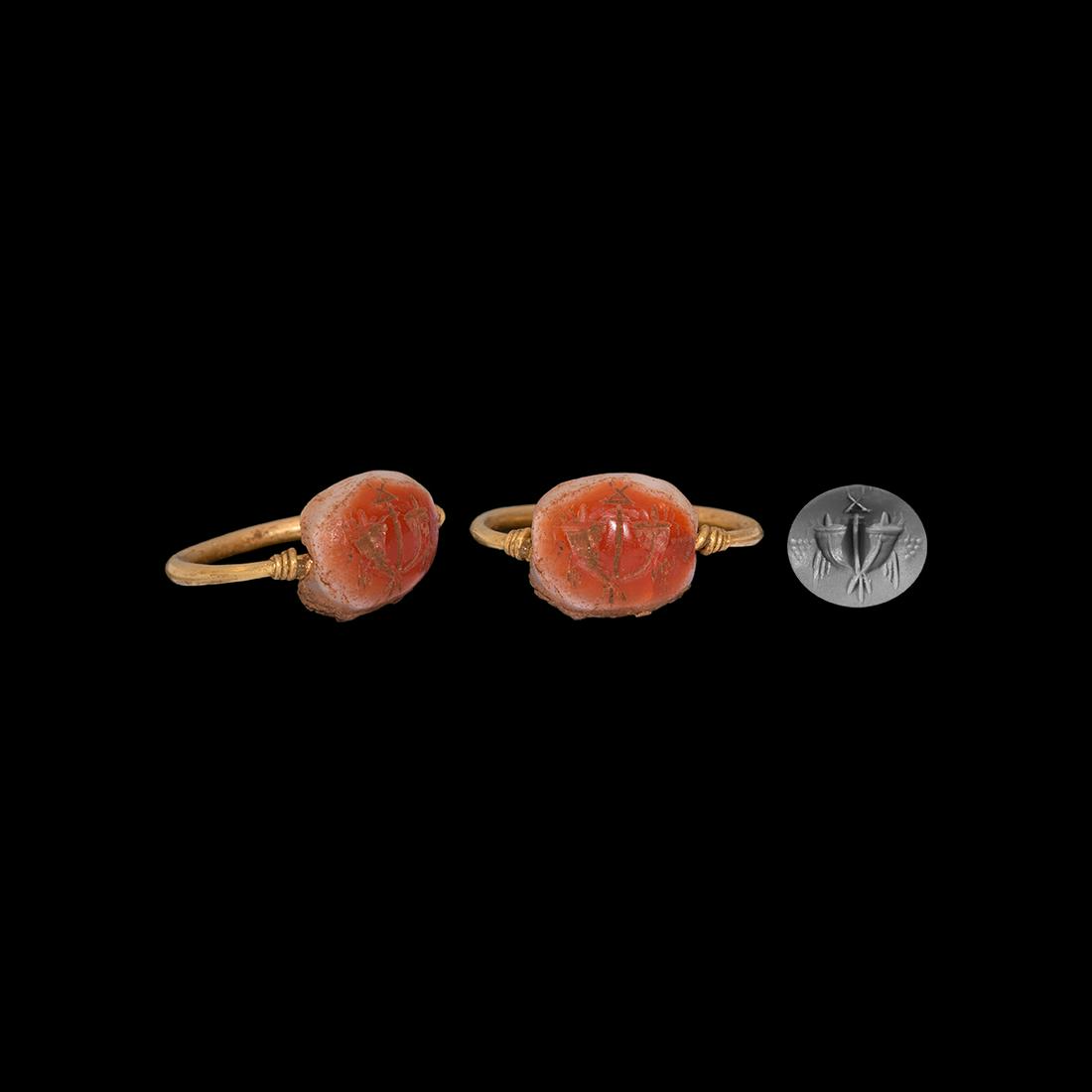 Roman Cornucopiae Gemstone in Gold Swivel Ring: 1st century BC-1st century AD. A banded carnelian scaraboid gem with intaglio vertical standard flanked by cornucopiae and bunches of grapes; in a possibly later gold swivel ring hoop. 5.49 grams, 28m