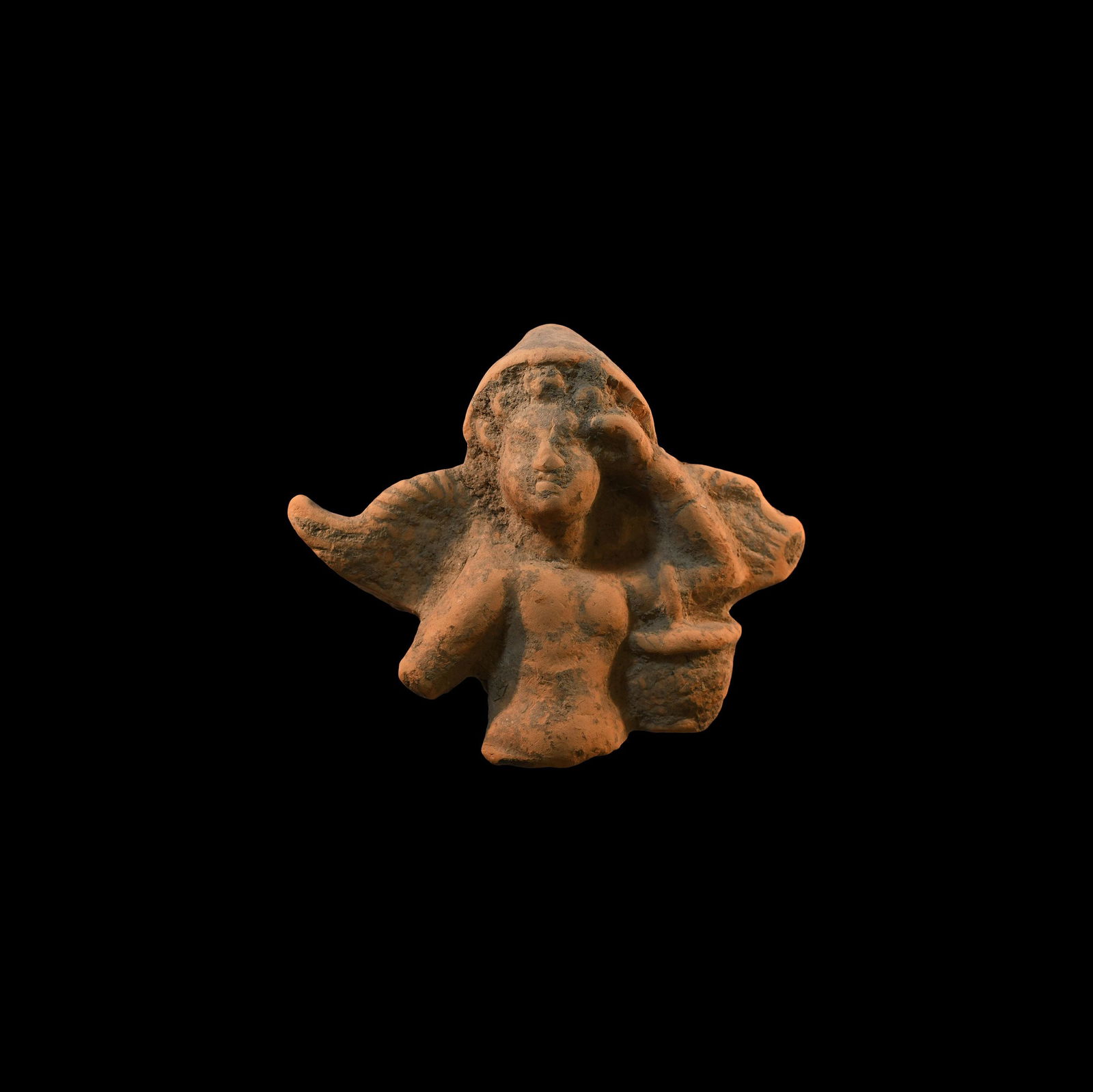 Roman Terracotta Mercury Fragment: 1st century BC-1st century AD. A terracotta moulded figure fragment of Mercury(?) in conical hood, left hand raised to the brow and a basket hung over the left upper arm. 52.4 grams, 81mm (3 1/4"). Pr