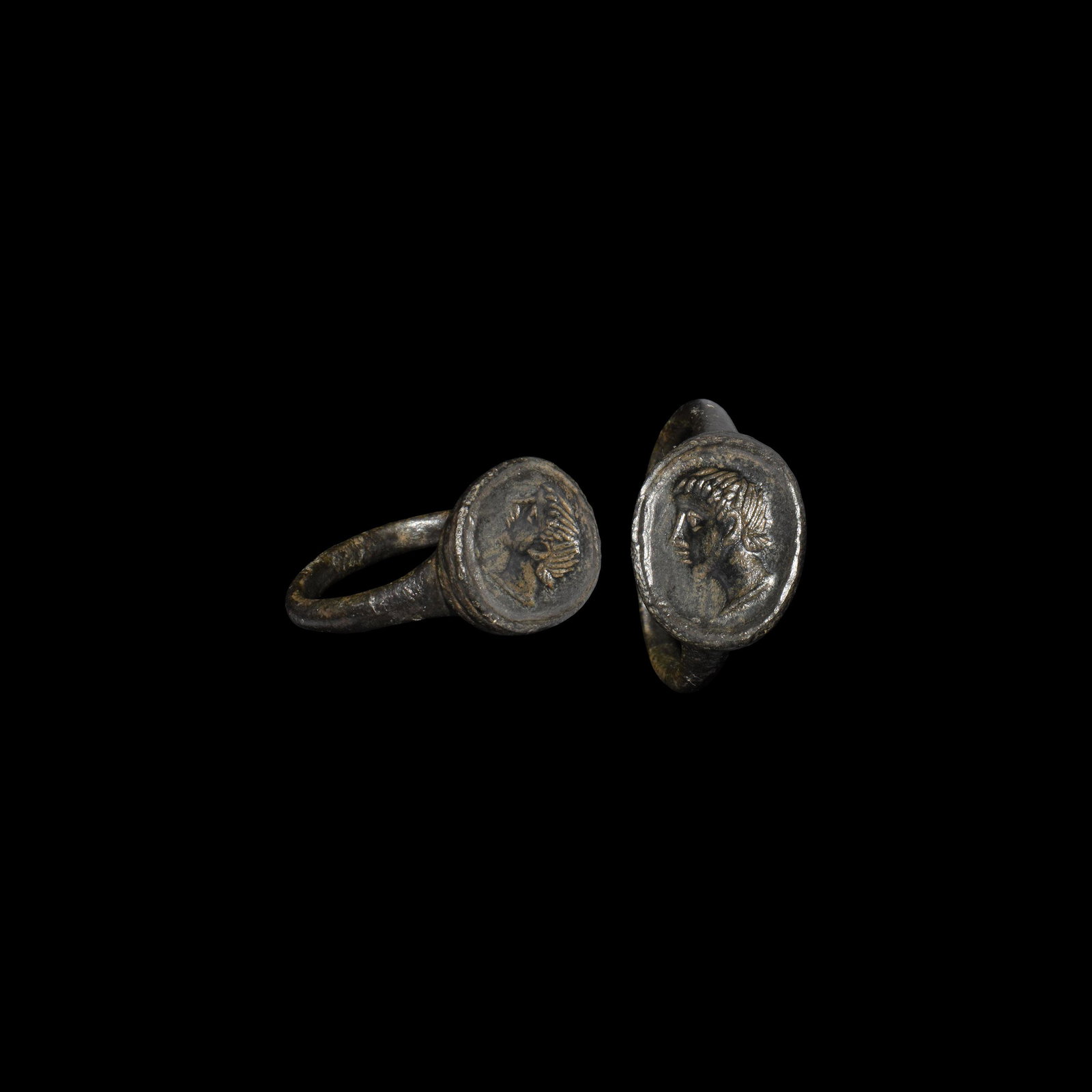 Roman Ring with Portrait: 4th century AD. A bronze finger ring with ellipsoid bezel, intaglio profile bust of a youthful male within a linear border. 5.14 grams, 21.03mm overall, 17.97mm internal diameter (approximate size Bri