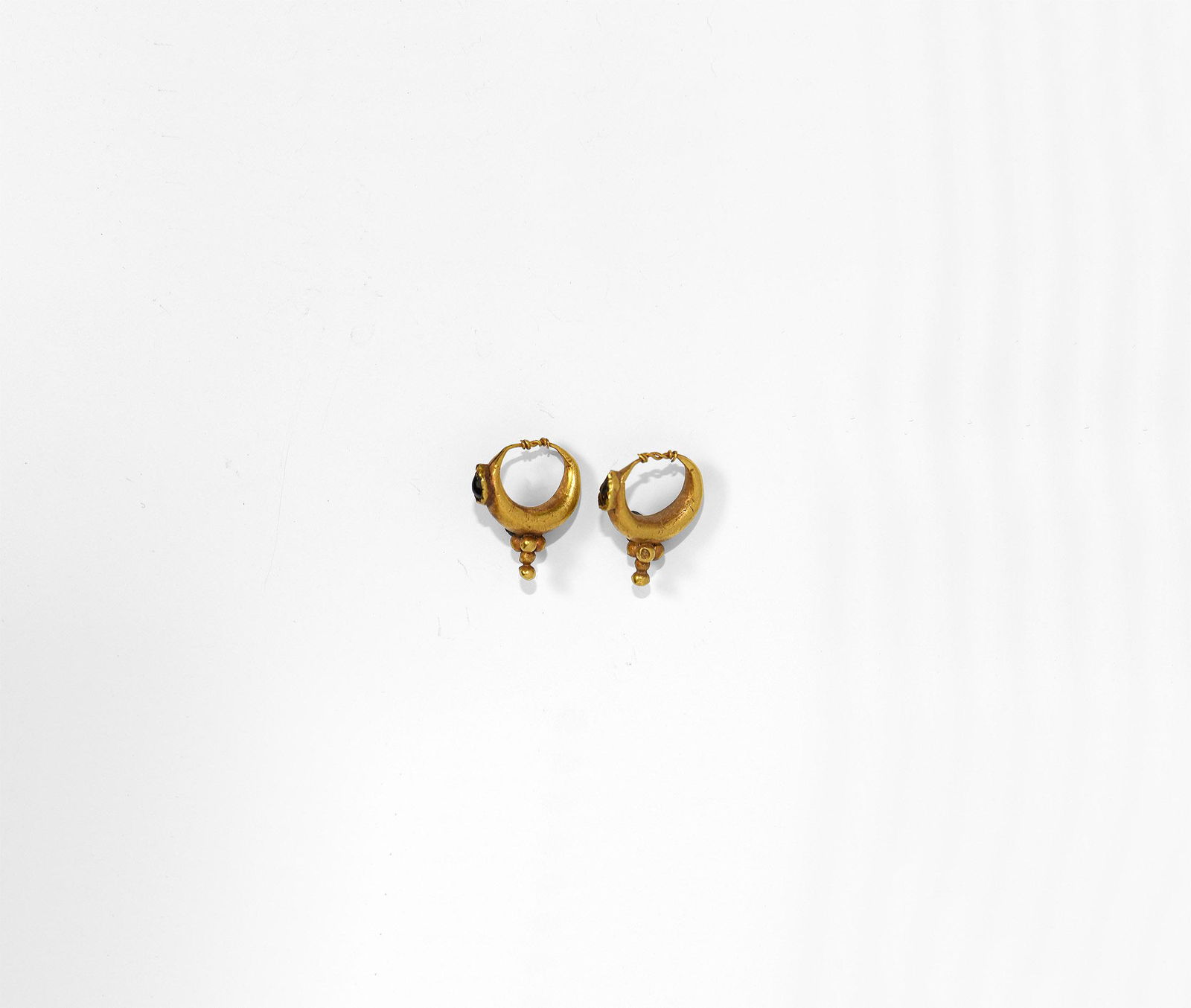 Roman Gold Earring Pair with Garnets: 2nd-3rd century AD. A pair of hollow-form gold hoop earrings with inset teardrop-shaped garnet, granule cluster below, twisted wire closure. 1.49 grams total, 17mm each (3/4"). Property of a London la