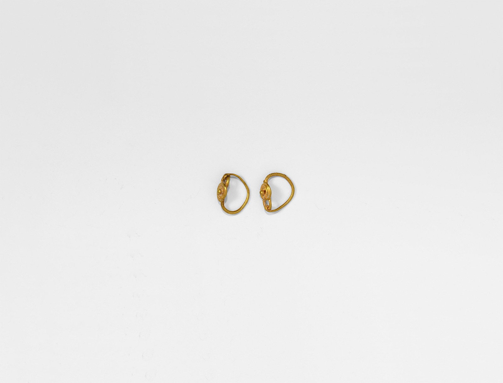 Roman Gold Earring Pair: 3rd century AD. A matched pair of delicate gold earrings, each a hook-and-eye, slender hoop, applied disc shield with granule. Cf. Ruseva-Slokoska, L. Roman Jewellery, Sofia, 1991, item 22. 1.00 grams