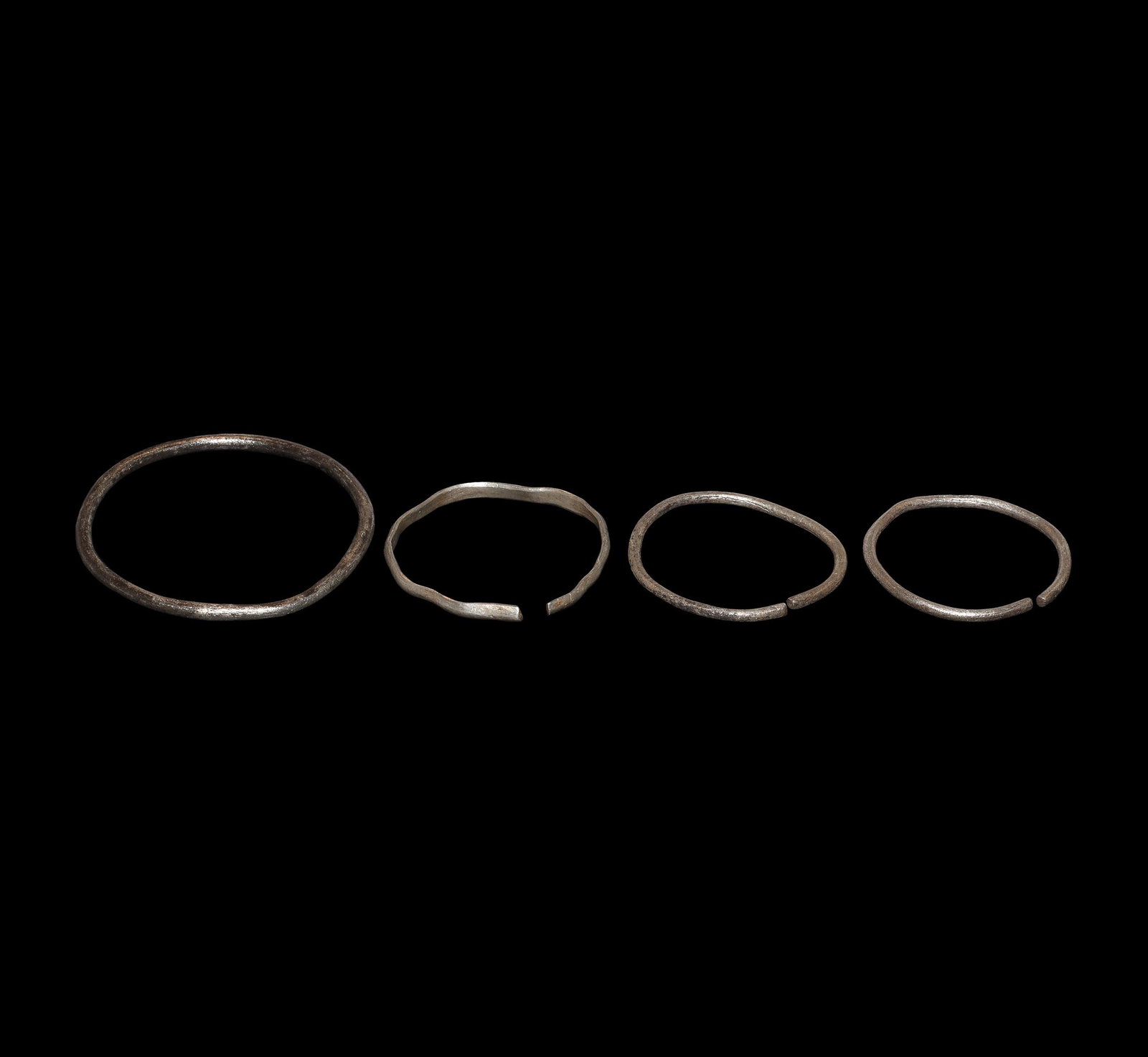 Viking Silver Bracelet Group: 9th-12th century AD. A group of four silver penannular bracelets, three round-section and one D-shaped. 44.6 grams total, 46-63mm (1 3/4 - 2 1/2"). From a private Netherlands collection; previously in