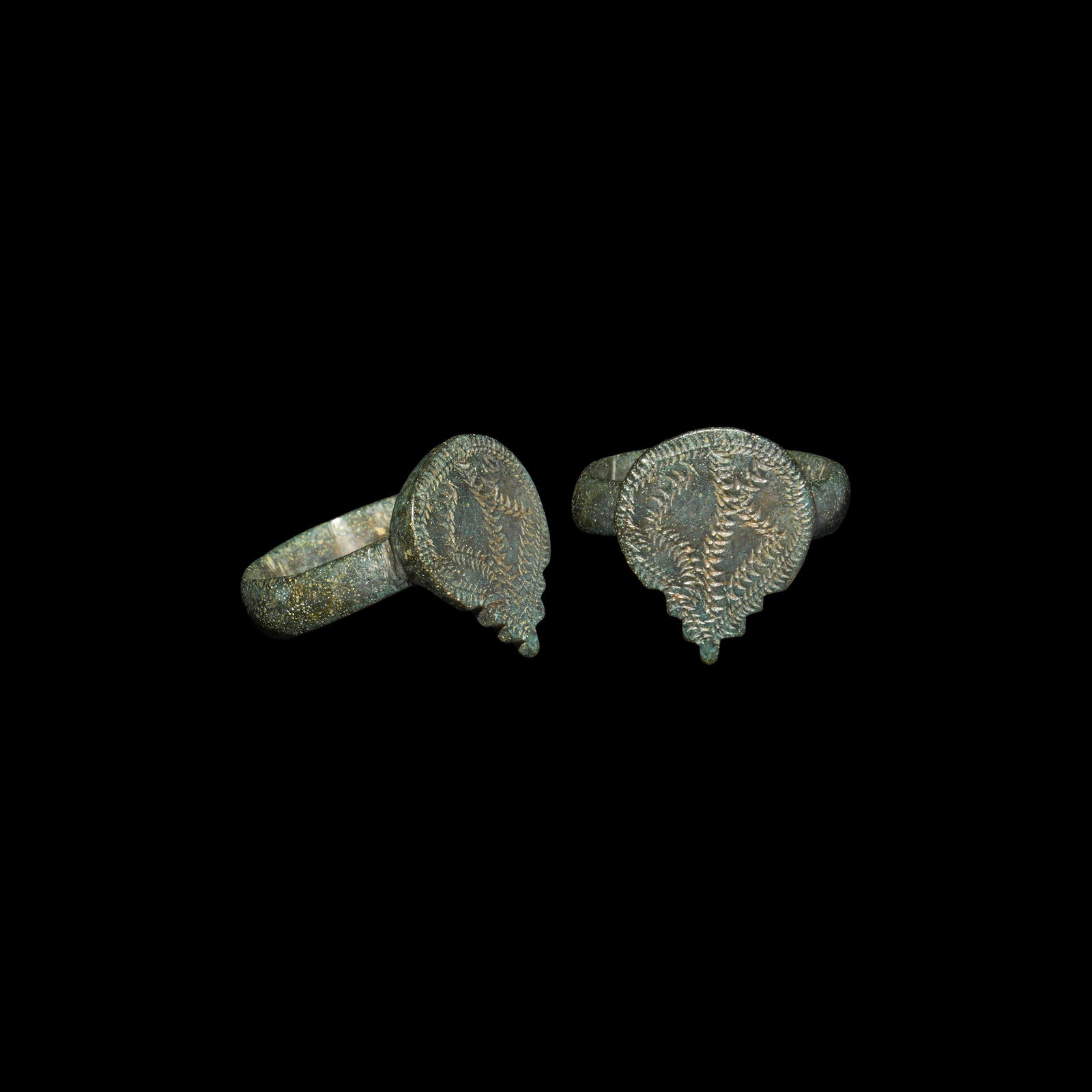 Medieval Ring with Teardrop Bezel: 13th-15th century AD. A bronze ring with teardrop-shaped bezel, the lower edge serrated, engraved leaf border with a central geometric zig-zag leaf design; the hoop D-shaped. 6.4 grams, 22.89mm overal