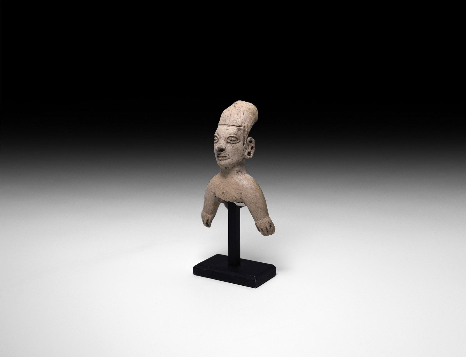 Pre-Columbian Terracotta Figure Fragment: 1st millennium AD. A hollow-formed grey ceramic figure with scooped headdress, nose and ear pierced to accept rings and other ornaments; mounted on a custom-made stand. 92 grams total, 13.5cm with sta