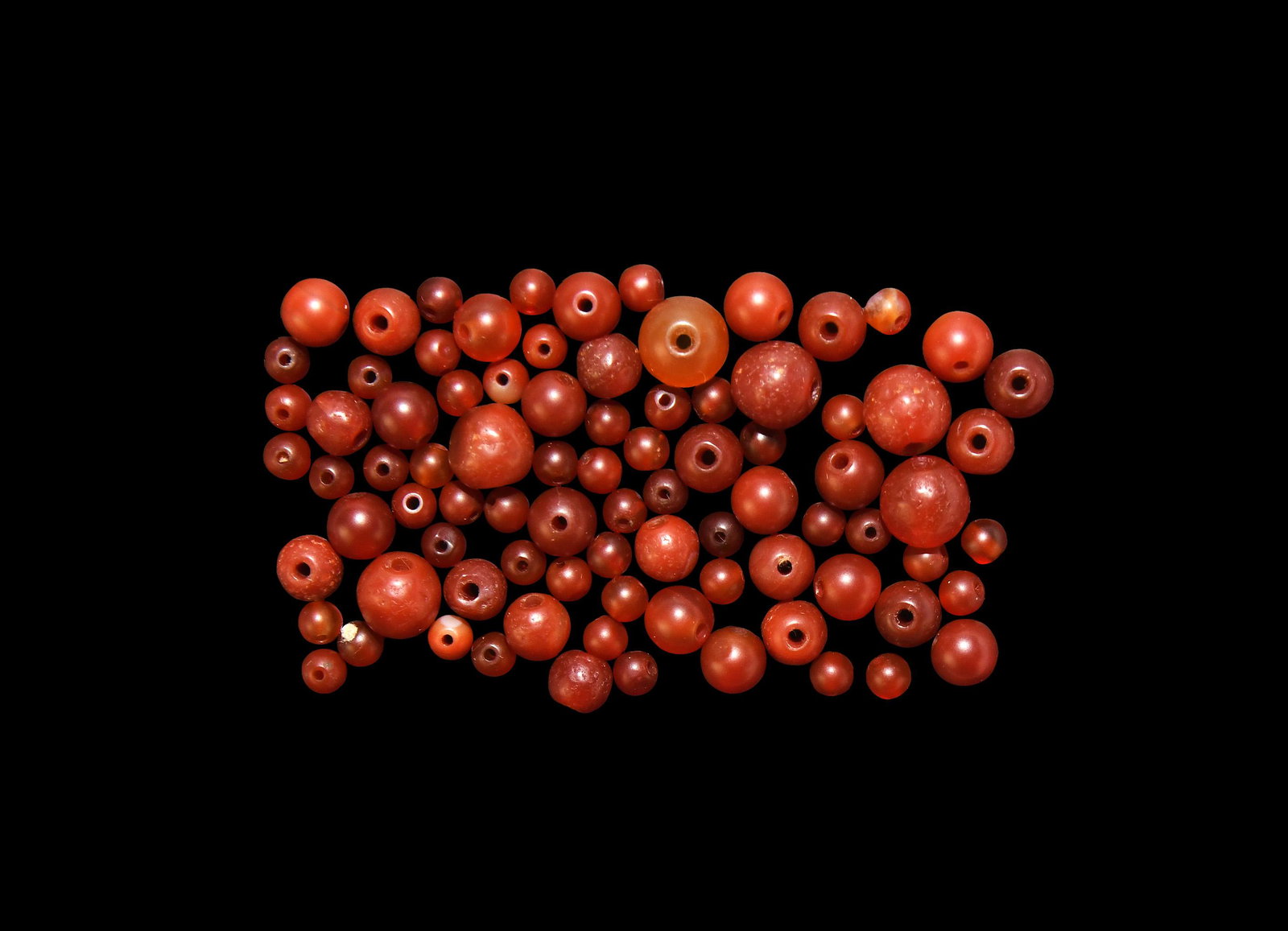 Egyptian Carnelian Bead Group: Roman Period, 30 BC-323 AD. A group of spherical red and orange carnelian beads of various sizes. 18.6 grams total. 4-8mm (1/4"). Property of a London collector, acquired early 1990s. [No Reserve]