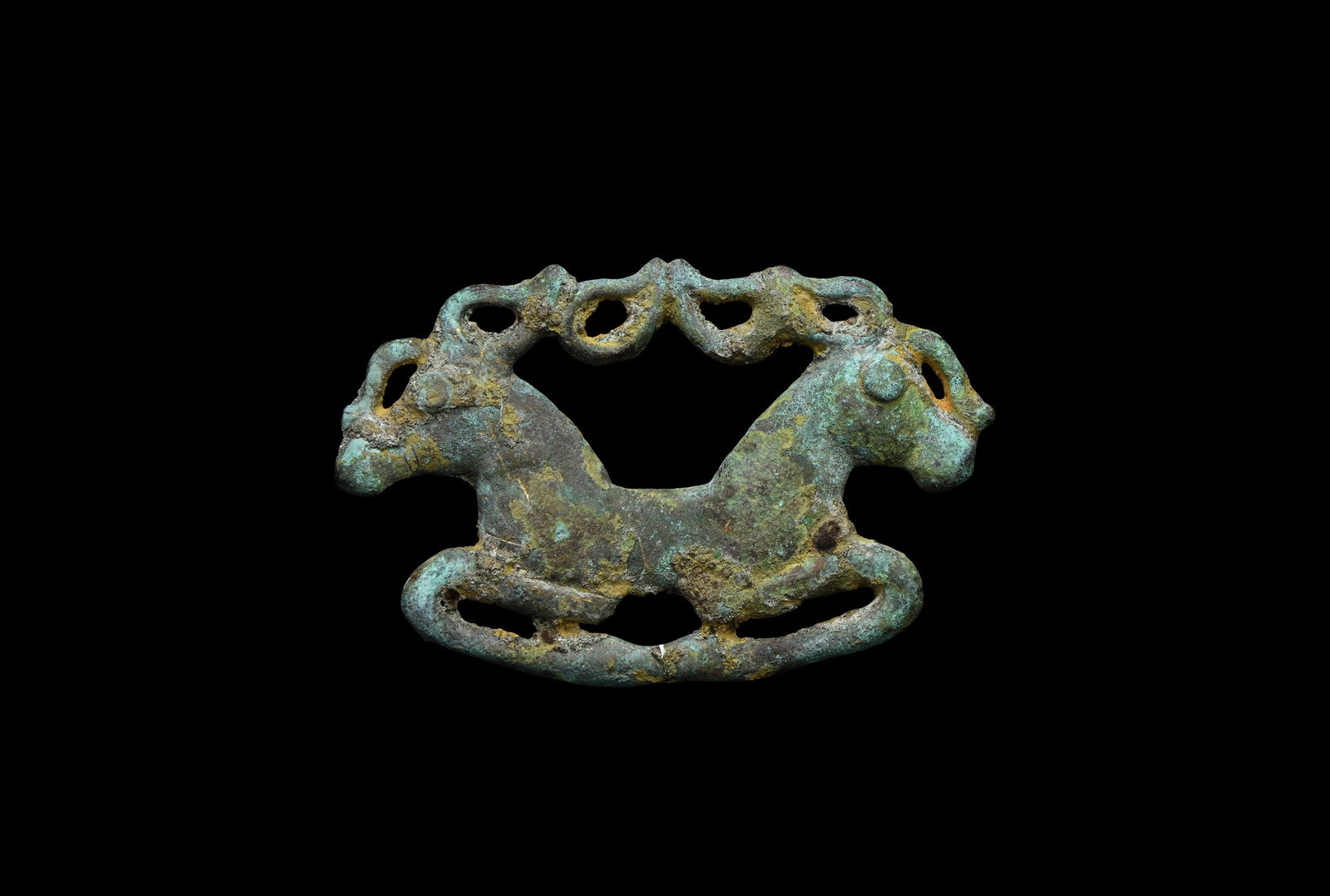 Scythian Galloping Double Stag Mount: 6th-2nd century BC. A bronze plaque mount formed as the foreparts of two galloping stags with their legs folded beneath the body, long antlers conjoining at the centre; two attachment lugs to the reve