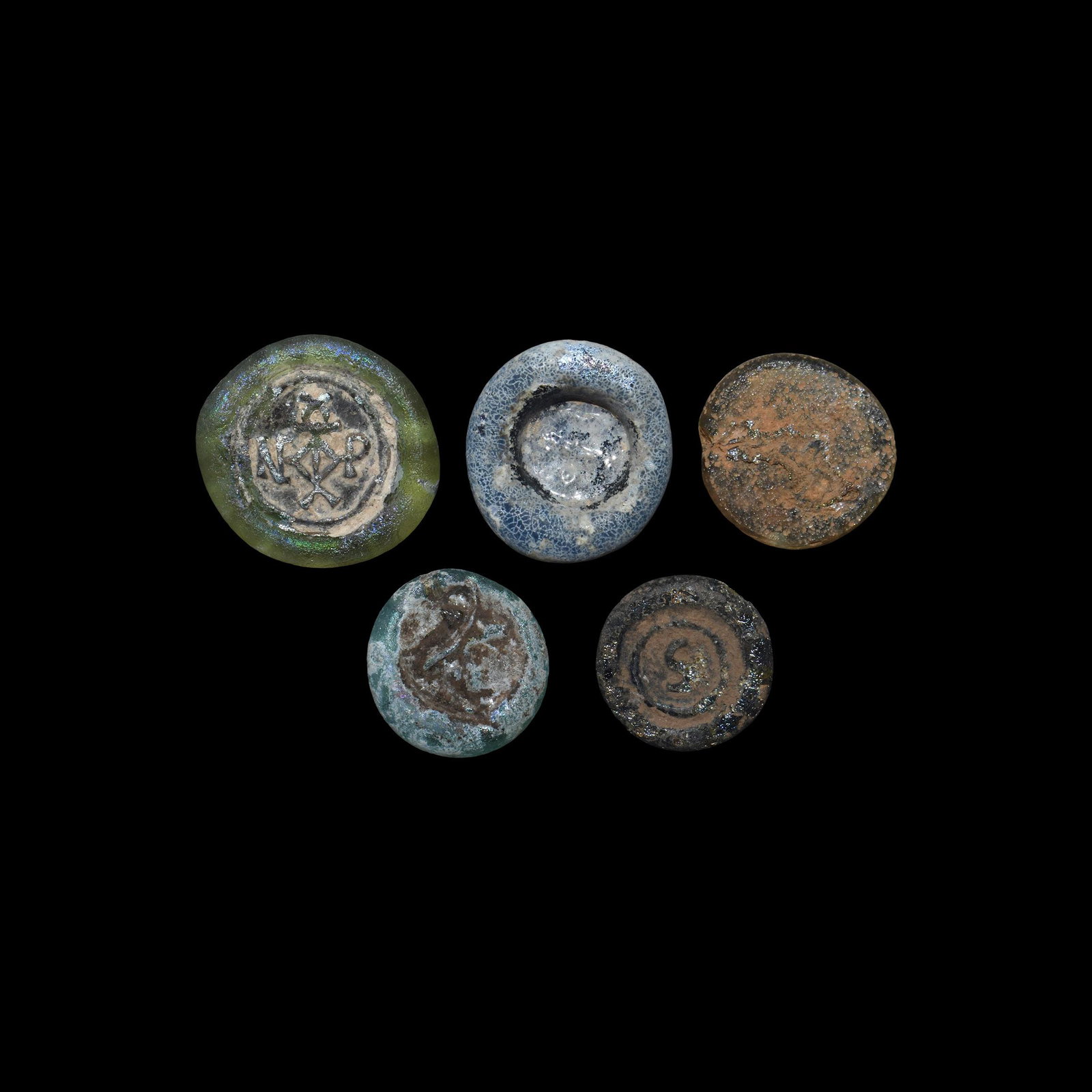 Byzantine Glass Token Collection: 5th-8th century AD. A mixed group of coloured glass tokens with impressed motifs including a monogram, dog and other designs. 7.73 grams, 16-22mm (1/2 - 3/4"). Property of a Bristol collector; formerl