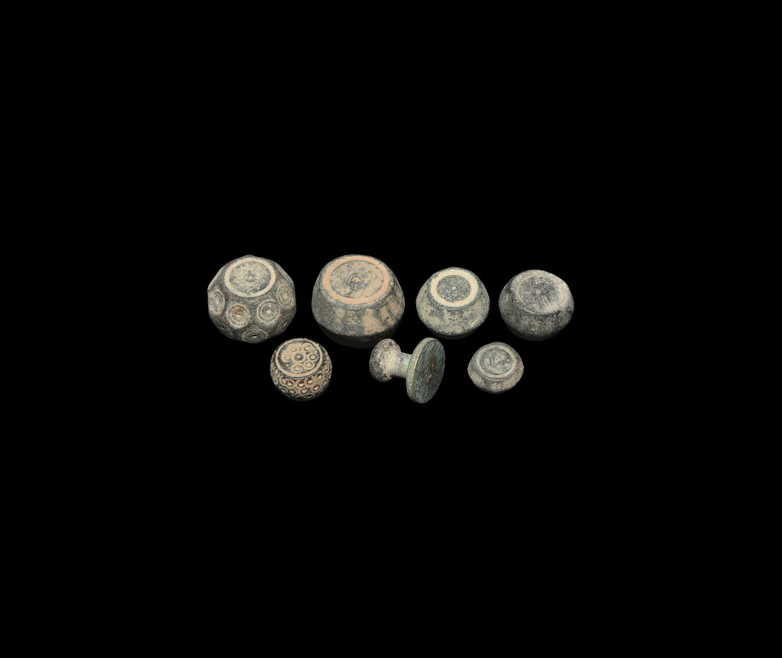 Byzantine Trade Weight Group: 6th-10th century AD. A group of seven bronze weights comprising: three biconical; one tabular with facetted edges; one barrel-shaped with stamped pellet-in-circle to all faces; one discoid with short