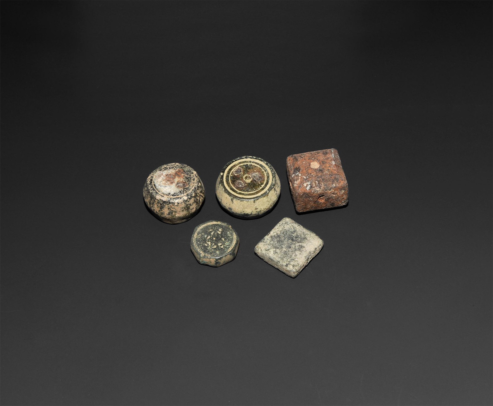 Byzantine Trade Weight Group: 6th-10th century AD. A group of five substantial bronze and iron weights comprising: an octagonal weight with stamped triangles to both faces; two biconical weight with concentric circles and triangle