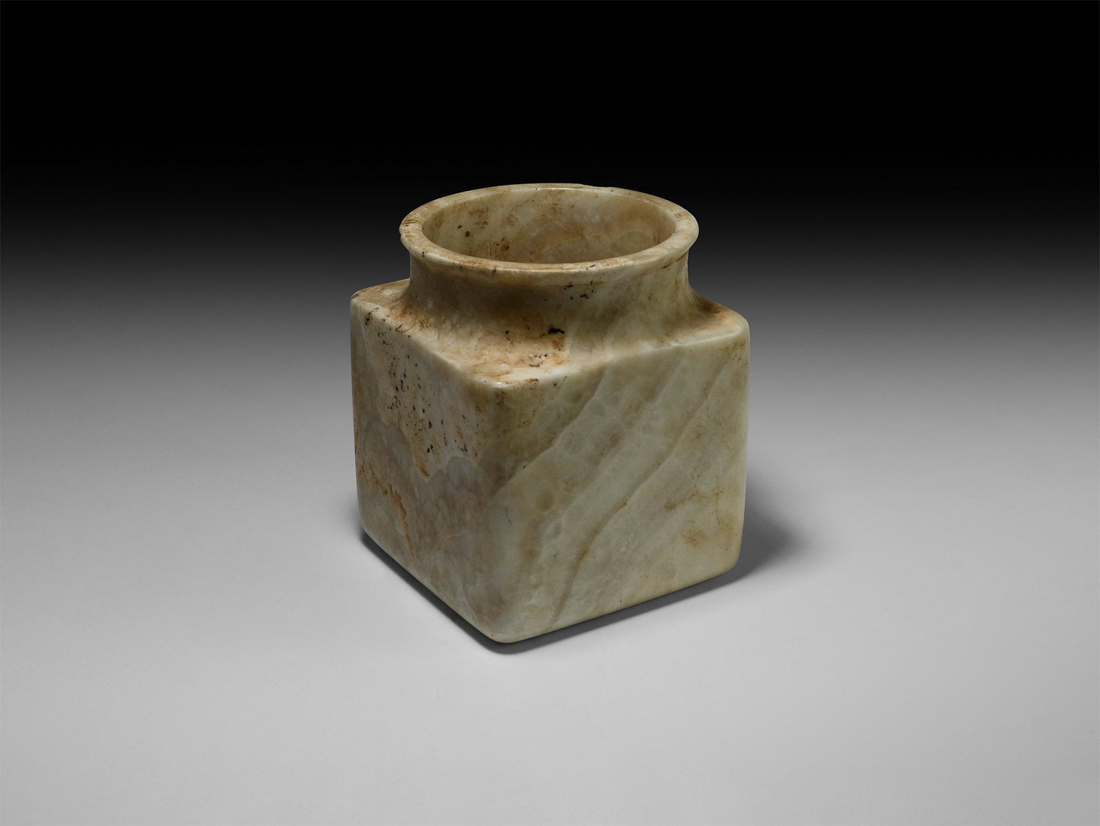 Western Asiatic Bactrian Alabaster Jar: 2nd millennium BC. A carved alabaster vessel, square in plan with waisted circular mouth, flange rim. 5.5 kg, 18cm (7"). From a North West London collection; previously acquired in the 1980s.