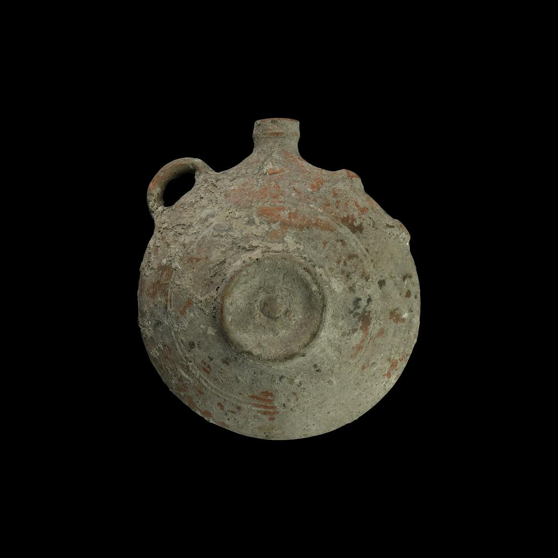 Western Asiatic Circular Flask: Early 2nd millennium AD. A terracotta discoid flask with central roundel and concentric rings to each face, loop handles to the shoulders and ribbed neck. 480 grams, 17cm (6 3/4"). From an important c