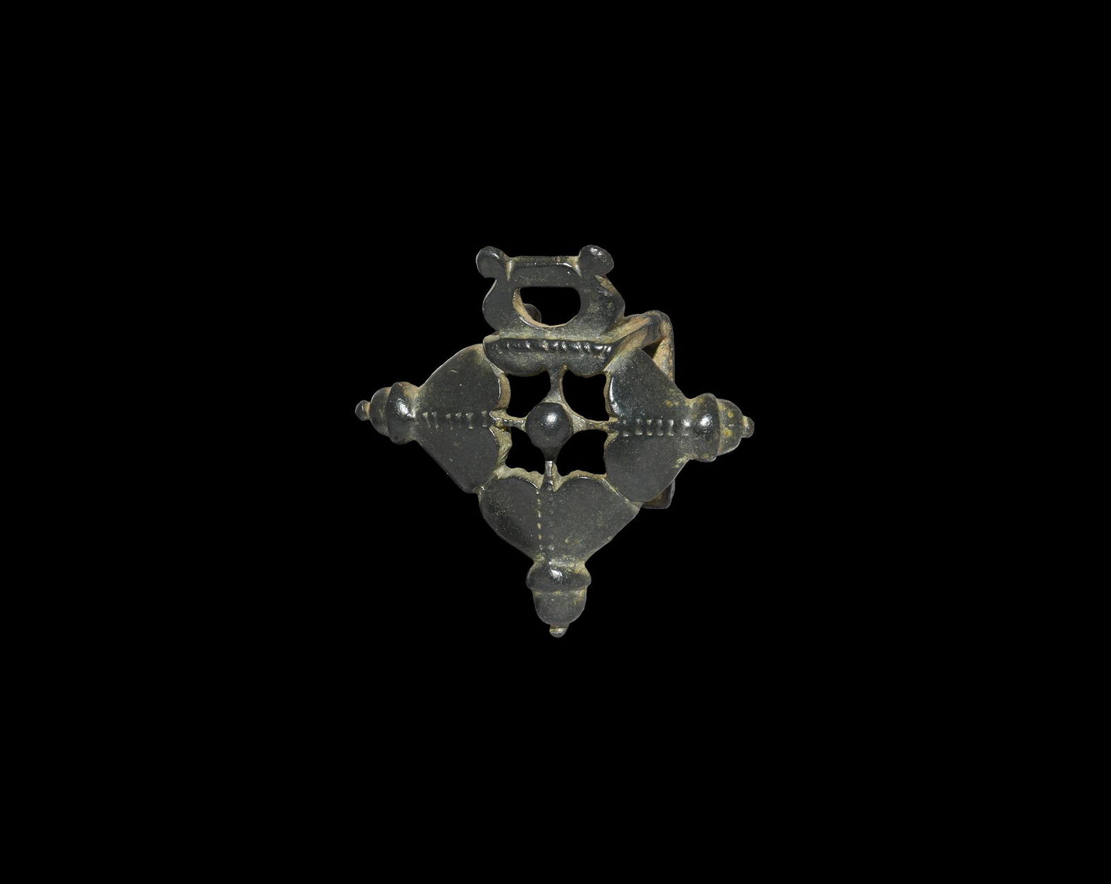 Medieval Dagger Strap Hanger: 12th-14th century AD. A bronze strap mount formed as a dished trefoil with strap attachment; frame formed as a set of three heart-shaped leaves with acorn-shaped collared knops on the outer edges and