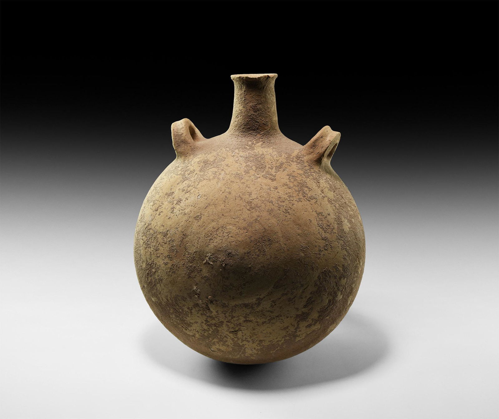 Western Asiatic Holy Land Pilgrim's Flask: 2nd-1st millennium BC. A substantial ceramic flask with discoid body, short flared spout and two gusseted loop handles to the shoulders. 2.6 kg, 30cm (11 3/4"). Ex North London gentleman; formerly in