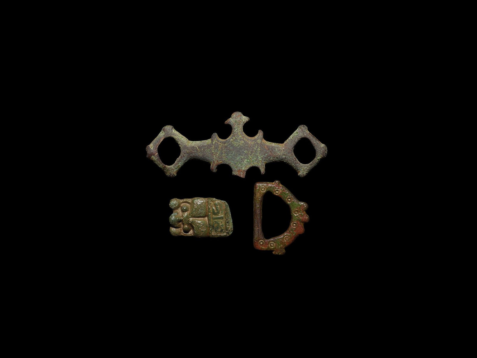 Anglo-Saxon and Viking Artefact Collection: 6th-11th century AD. A mixed bronze group comprising: a panel from a cruciform brooch with facing mask; a buckle loop with lugs to the outer edge and ring-and-dot motifs; a harness or bridle strap dis