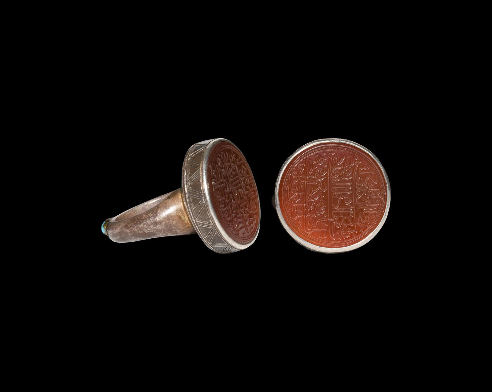 Islamic Silver Ring with Calligraphic Gemstone: 20th century AD. A silver finger ring with large discoid bezel, inset carnelian plaque with dense nasta'liq calligraphic text. 23.20 grams, 36.07mm overall, 20.38mm internal diameter (approximate size