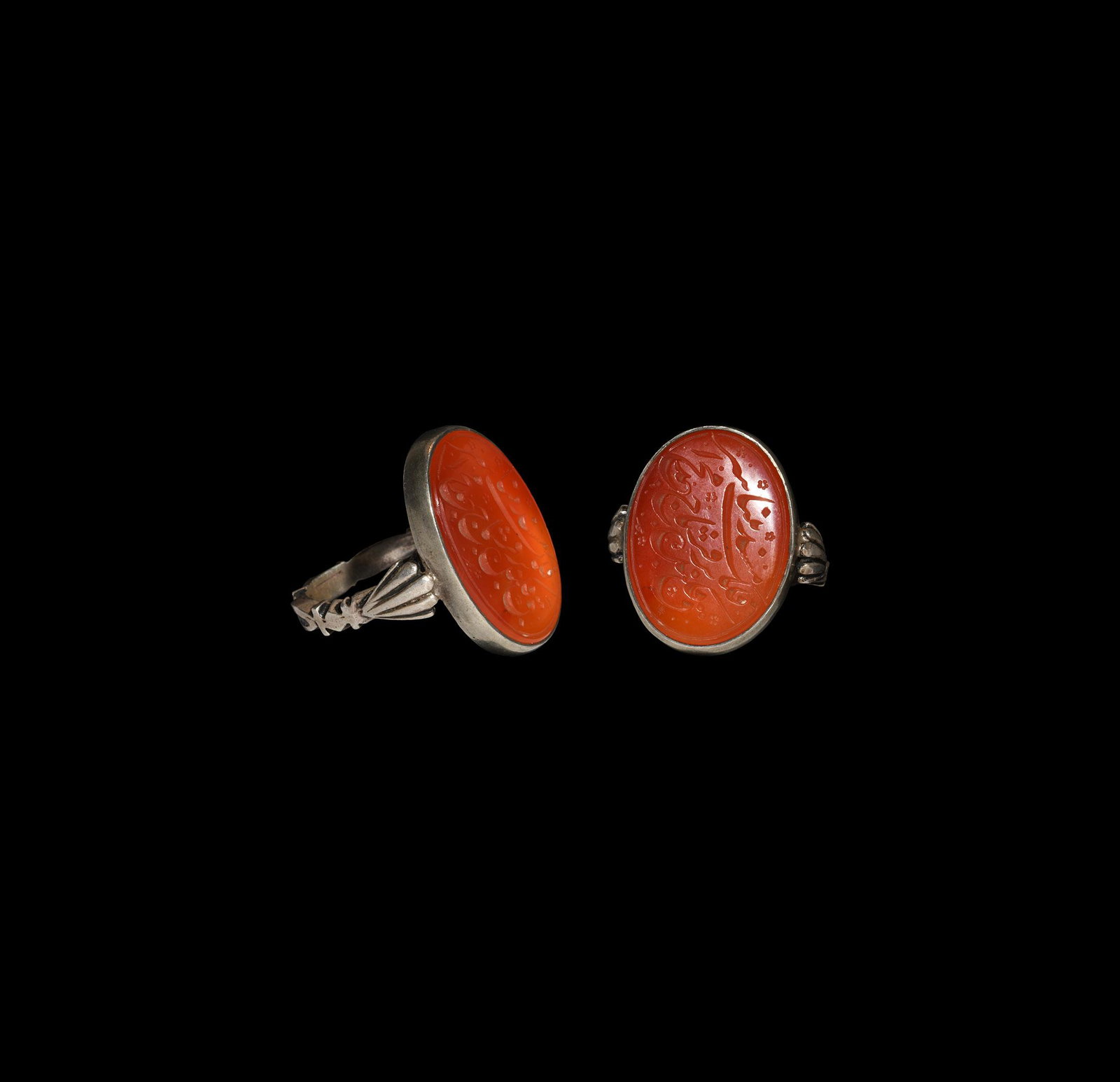 Islamic Silver Ring with Calligraphic Gemstone: 20th century AD. A silver finger ring with scalloped shoulders, ellipsoid cell with inset carnelian cloison, inscribed nasta'liq calligraphic legend. 15 grams, 30.44mm overall, 21.75mm internal diamet