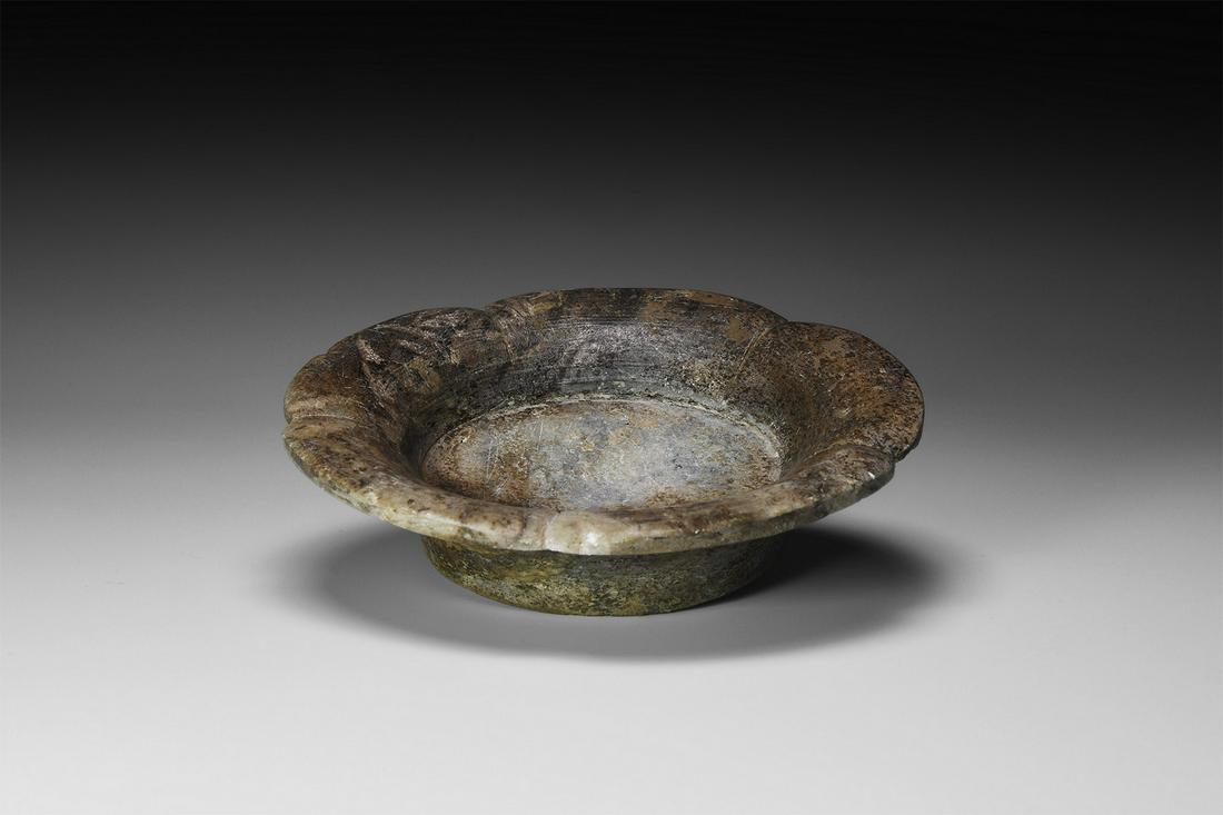 Chinese Green Stone Petalled Dish: 19th century AD. A green stone dish formed as a lotus flower, with truncated trumpet-shaped body and rim with notches and grooves. 182 grams, 10.7cm (4 1/4"). From the collection of the late C Roger M