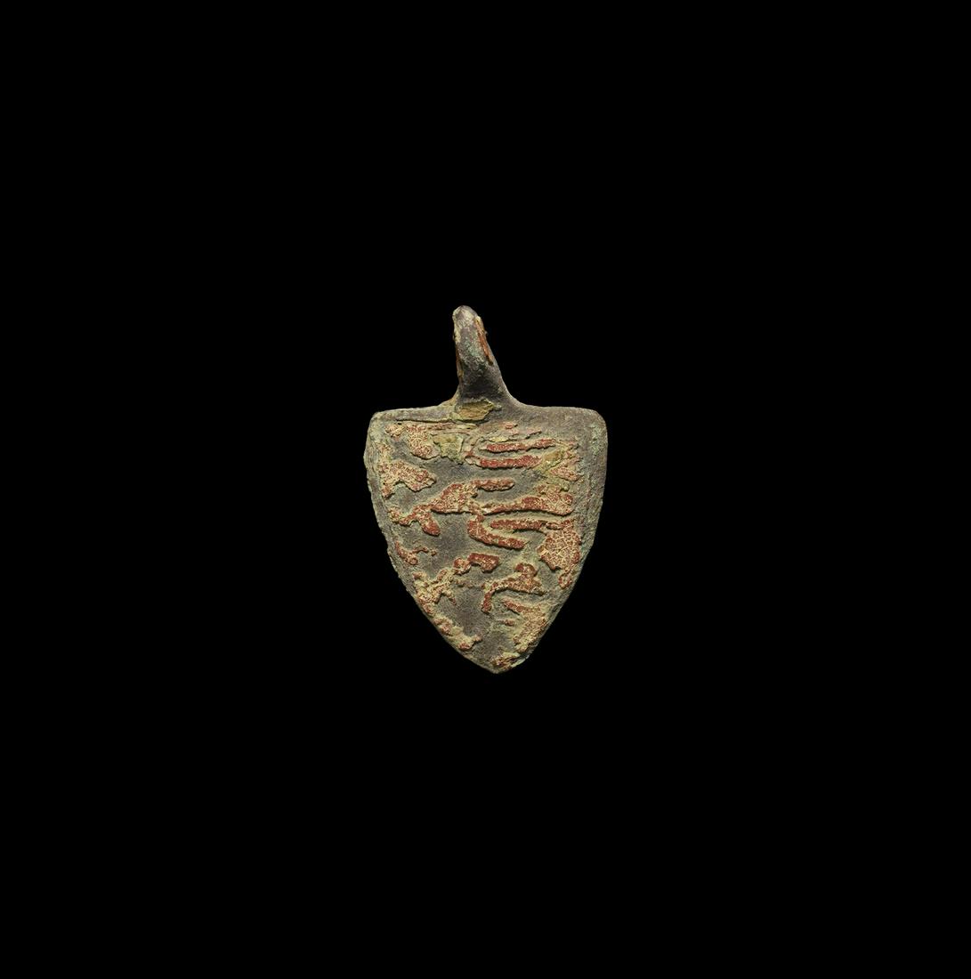 Royal Arms of England' Horse Harness Pendant: 14th-15th century AD. A heater shield-shaped horse harness pendant with integral suspension loop; the field in red enamel with three reserved lions passant gardant; traces of gilding. Cf. Ashley, S., 