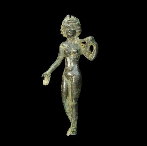 Roman - Venus Statuette: Circa 1st-2nd century AD. A cast bronze statuette of the goddess Venus, nude and in advancing stance with extended right hand; her left arm bent to support her plaited hair in her left hand; her hair 
