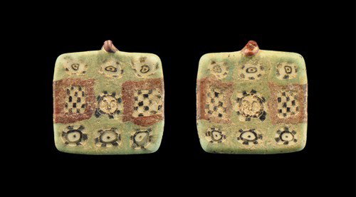 Roman - Mosaic Glass Tessera Pendant: Circa 1st-2nd century AD. A pale green glass pendant produced by the millefiori method comprising a central face within chequered surround, flanked by two chequered squares with red borders; above and