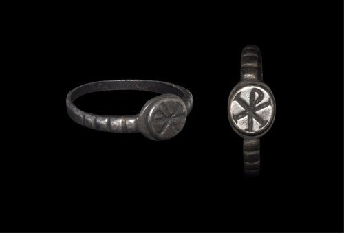 Byzantine - Silver Chi-Rho Seal Ring: Circa 5th-7th century AD. A plain silver hoop rising to segmented shoulders; the elliptical bezel with inscribed seriffed chi-rho symbol on a raised panel; traces of inscription on the interior of the
