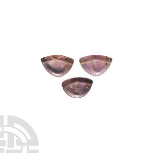 Egyptian Amethyst Mandrake Amulet Group: New Kingdom, 1550-1070 B.C. A group of three amethyst amulet beads formed as mandrake fruit, each roughly semi-circular in shape with a lentoid-section body and notched arched edge to both faces;